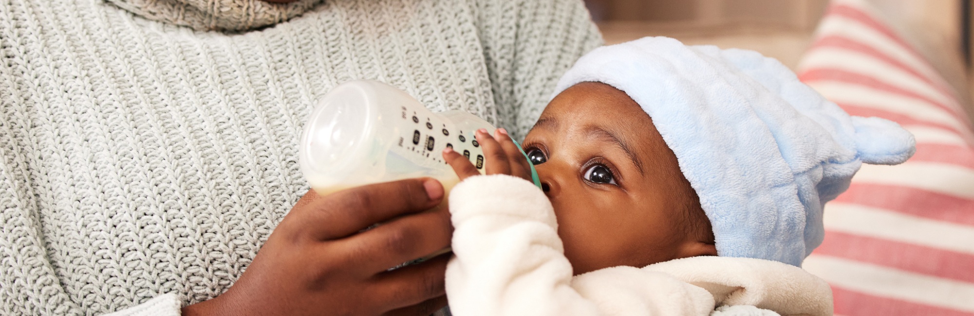 dark skinned baby drinks from bottle