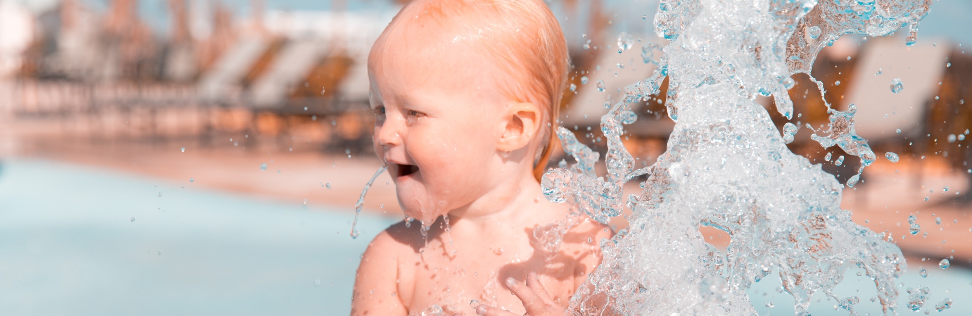 baby plays in water fountain