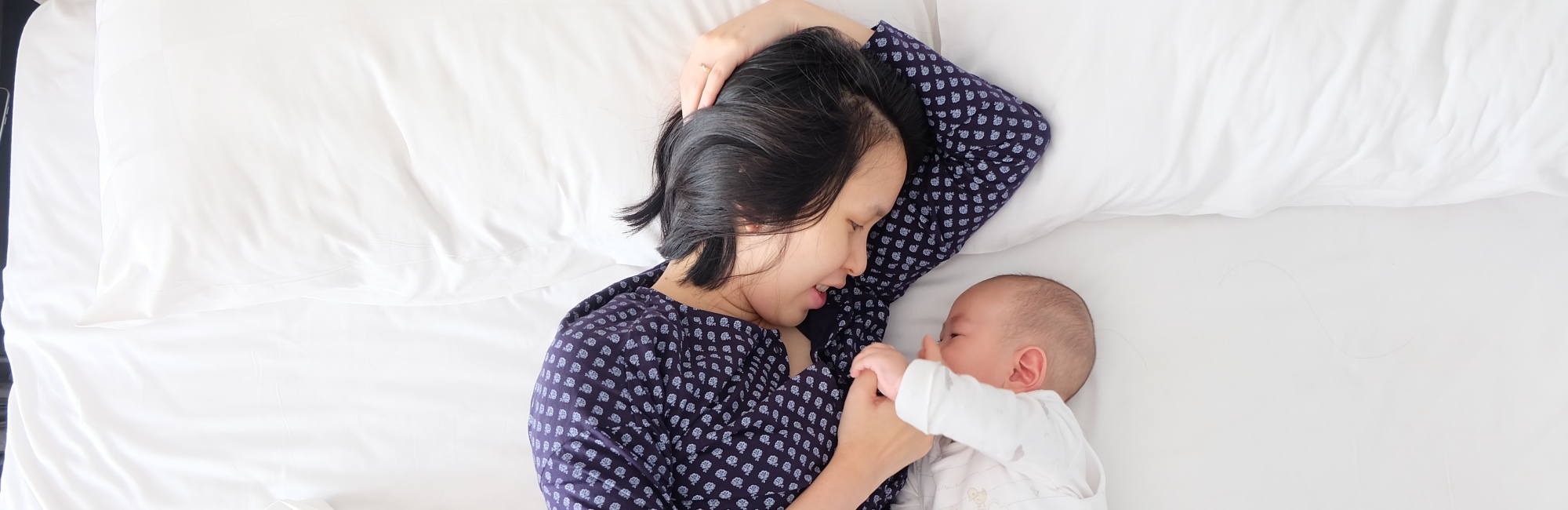 mother and baby play safely in bed