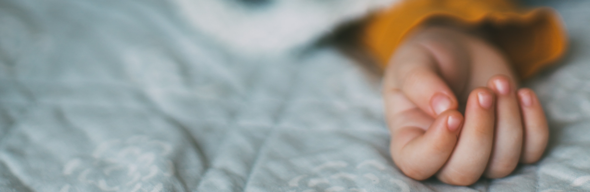 close up of small child's hand in bed