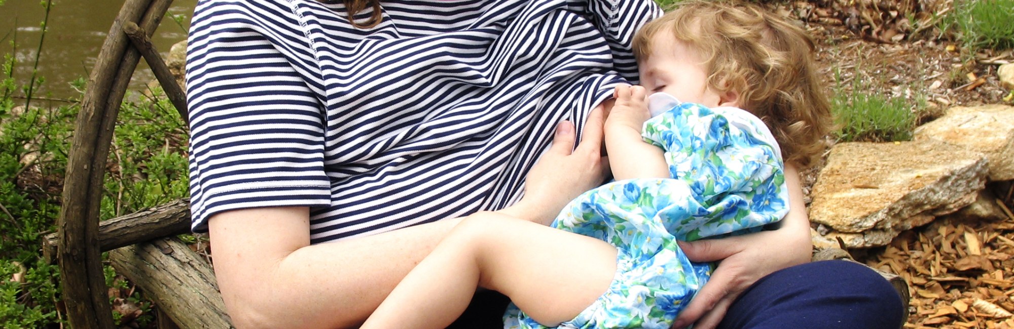 toddler takes a quick breastfeed on the go in park
