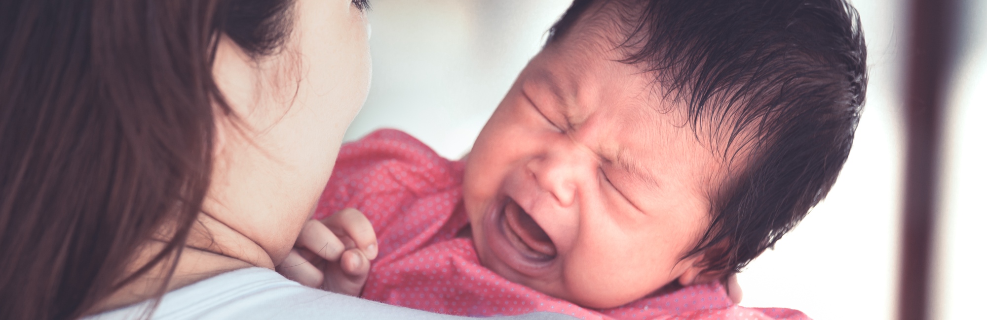 mother holding up crying baby