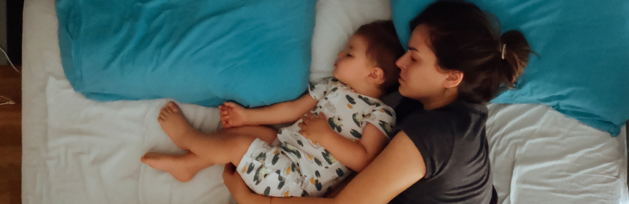 mum and toddler sleeping together cuddled up in bed