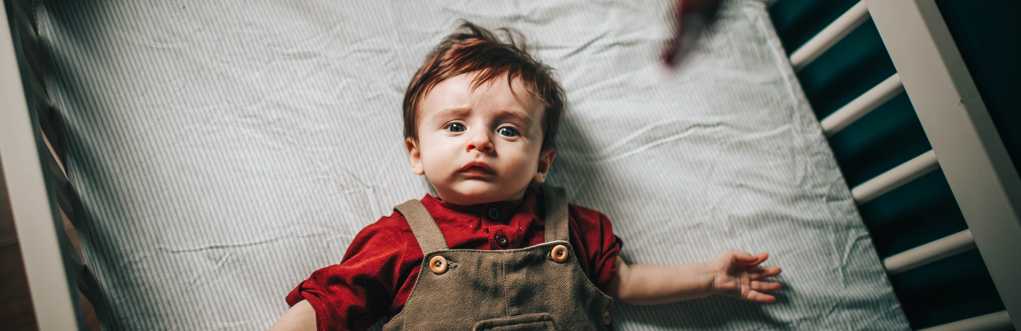 toddler looking confused laying on cot