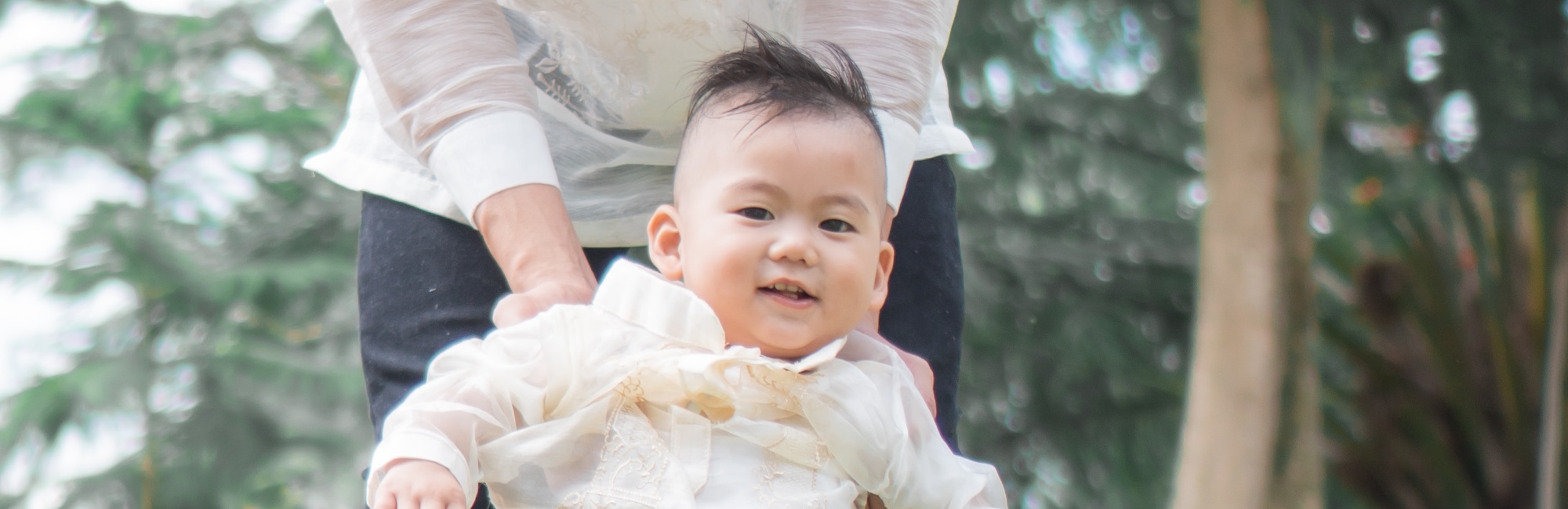 happy toddler plays outside in park with parent